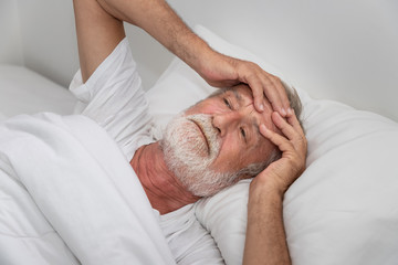 Fototapeta na wymiar Senior elderly man on bed eye open sleeplessness and worry, with white blanket in bedroom