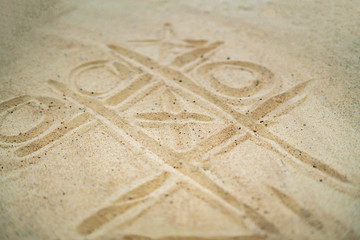 hand drawing tic tac toe playing on the sand in the summer beach