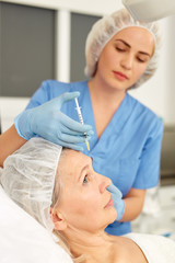 Senior woman getting injection for facial rejuvenation procedure in esthetic clinic