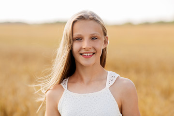 nature and people concept - smiling young girl on cereal field in summer