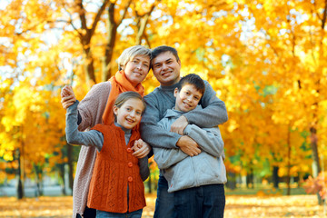 Fototapeta premium Happy family posing, playing and having fun in autumn city park. Children and parents together having a nice day. Bright sunlight and yellow leaves on trees, fall season.