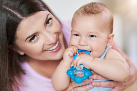 Mother And Her Newborn Baby With Teething Ring