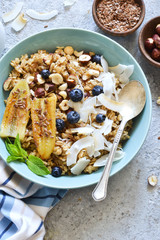 Oatmeal with caramel, banana, blueberries and coconut chips on a concrete background.