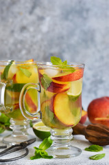 Cold summer drink with peach, lime and mint on a concrete background.