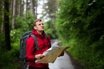 Man with backpack exploring forest,using map