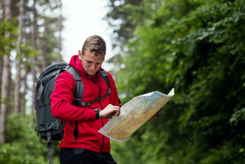 Man with backpack exploring forest,using map