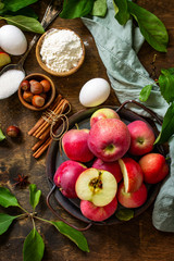 Apple baking seasonal concept. Ingredients for apple pie (red apple, flour, eggs, anise, sugar, hazelnut and cinnamon) on a rustic wooden table. Top view flat lay.