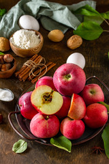 Apple baking seasonal concept. Ingredients for apple pie (red apple, flour, eggs, anise, sugar and cinnamon) on a rustic wooden table.