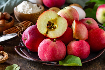 Apple baking seasonal concept. Ingredients for apple pie close-up (red apple, flour, eggs, anise, sugar, hazelnut and cinnamon) on a rustic wooden table.
