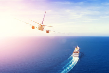 Cruise ship goes into the open sea, plane flies into the sky horizon in the evening at sunset....
