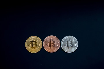 Three bitcoin, gold, silver, copper on black background