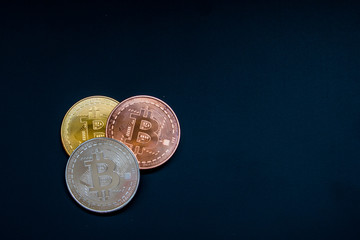 Three bitcoin, gold, silver, copper on black background