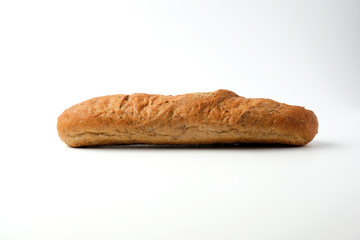 side view of a baked rye flour baguette on a white