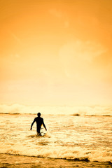 Fototapeta premium Surfer on the beach and sandy sea shore with the beautiful golden sunset view.
