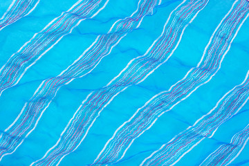 Blue wavy organza fabric with diagonal stripes. Blue abstract cloth background