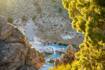 Backlit, natural framed scene of the Hot Creek Geological Site, focus on the teal water