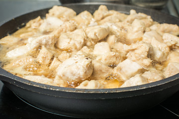 Slices of juicy chicken with gravy stew in pan on stove.