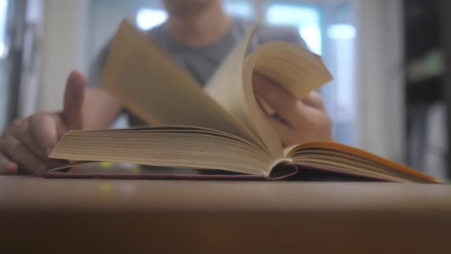 man is reading a lifestyle book. education learning library concept. man opens the book. man turns the pages of the book slow motion video