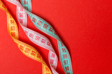 Close up of colorful measure tapes on red background. Perfect female figure measurements concept