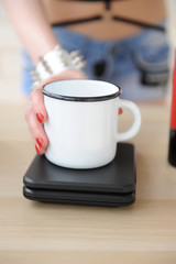 Girl puts a white cup on the scales close up. Coffee brewing