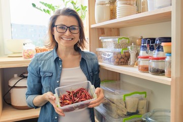 Woman in pantry holding container with red bitter chili pepper