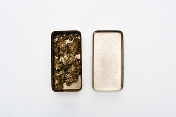 flat lay with marijuana buds in metal container on white background