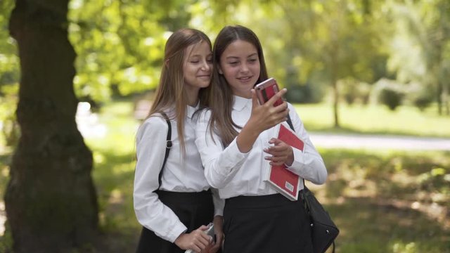 Two young school girls taking selfies on a smartphone