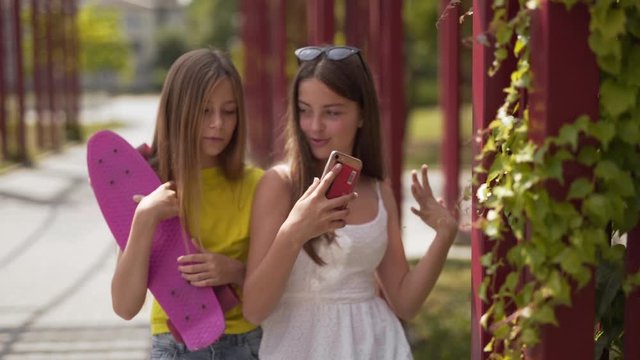 Two young teenage girls excitedly using an app on a smartphone