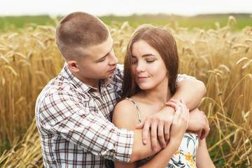Young couple in love in a wheat field. Man and girl hugging in nature, close-up