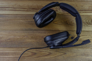 Black headphones with a microphone on a wooden table.
