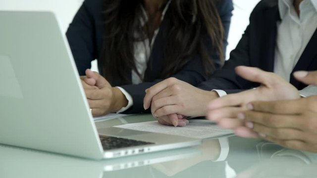 Cropped shot of business people sitting at table with laptop. Closeup shot of managers sitting in row at table with laptop. Business concept
