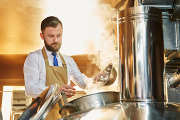 Serious man brewing beer a factory