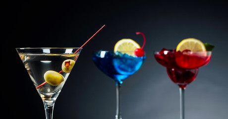 Two colorful cocktails and dry martini with green olives.