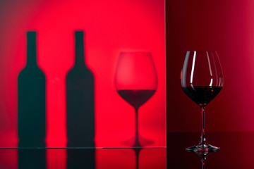 Bottles and glasses of red wine on a black reflective background.