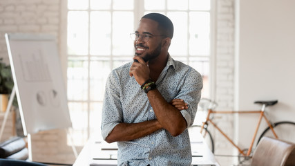 Dreamy happy african business man thinking of success in office