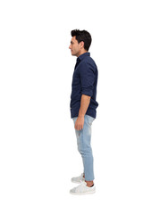 Side view of a young casual man standing isolated on white background