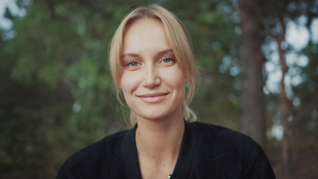 Portrait of a Young Beautiful Blond Woman in a Romantic Nature Atmosphere with a Forest in the Background. She is Confident and Smiling. She Has Green Eyes. Summer in the Woods.