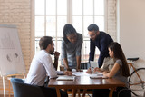 Multiracial business team cooperating discussing paperwork at office table