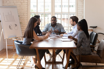 Focused diverse team listen african leader sit at boardroom table