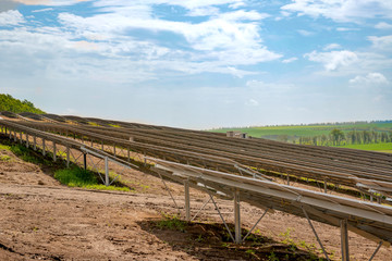 Fototapeta na wymiar Rows of solar panels on the steep hills of the field