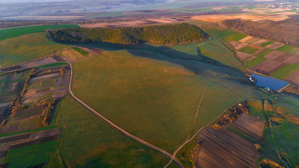 A plain with fields and a small forest, shot from above.