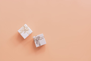 Flat lay two holiday gift boxes of gray and white on a pastel pink background. Top view, copy space.