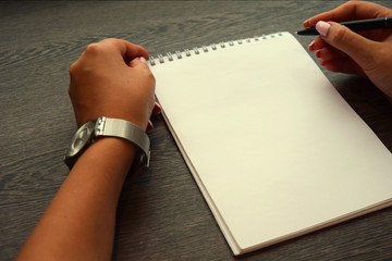Female hands with pen writing in notebook toned