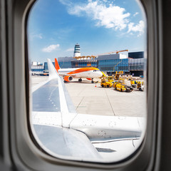 View from the window of the aircraft on the taxiway and the airport building with the airplane