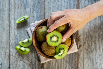 Fresh kiwi fruit in the bowl on wooden background