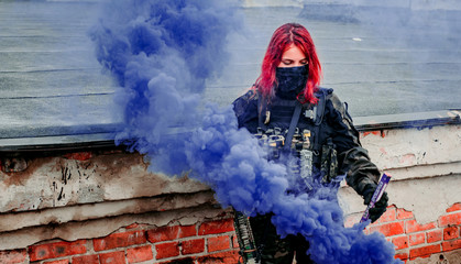 Airsoft red-hair woman in uniform with violet smoke on roof. Close up soldier. Horizontal photo