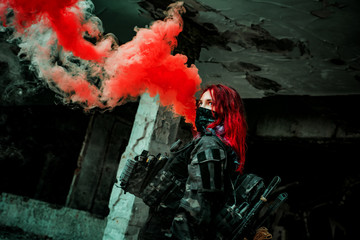 Airsoft red-hair woman in uniform with red smoke in hand. Close up soldier in broken building. Horizontal photo