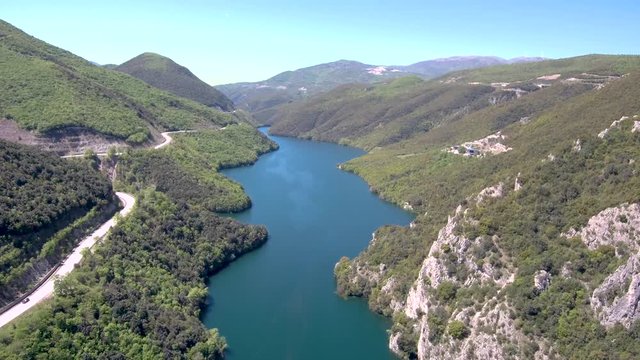 Aerial view of Aliakmonas river in valley and country road on the side, Veria Greece,  motion in front of a drone