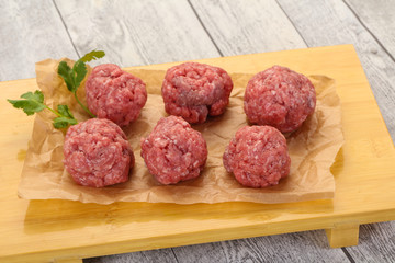 Raw meatball over wooden background