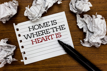 Text sign showing Home Is When The Heart Is. Conceptual photo Your house is where you feel comfortable and happy Paper lumps laid randomly around white notepad touch black pen on woody floor